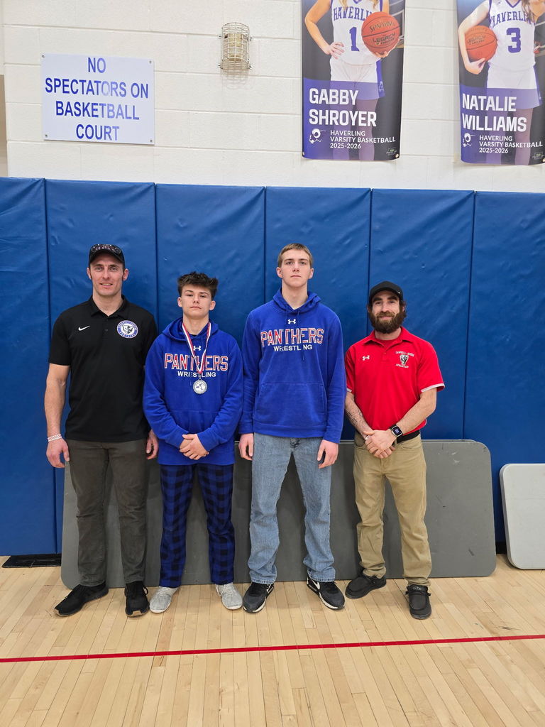 Two wrestlers posing with coaches.