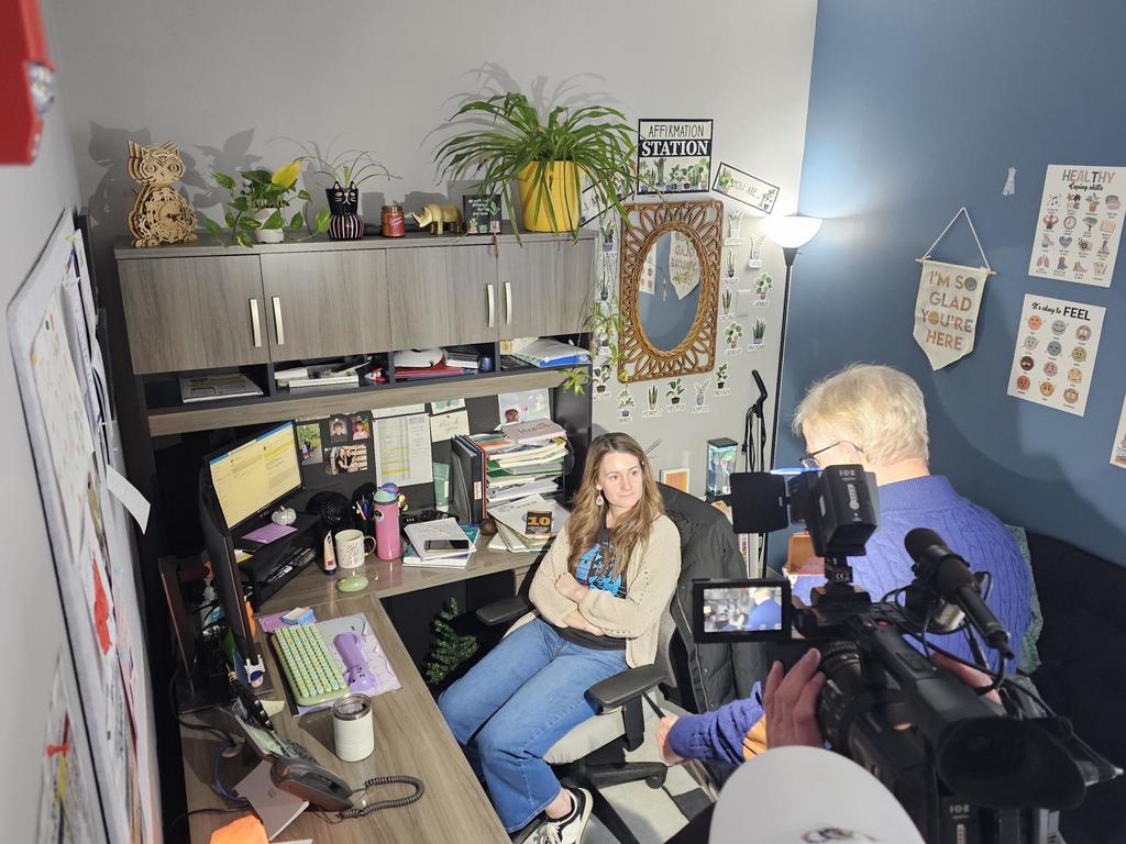 adult in chair with news cameras in office interview her for Golden Apple Award