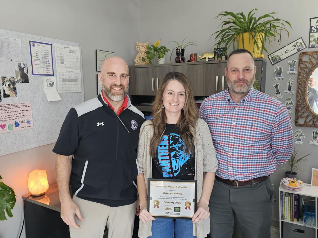 three adults standing with the middle adult holding a certificat award