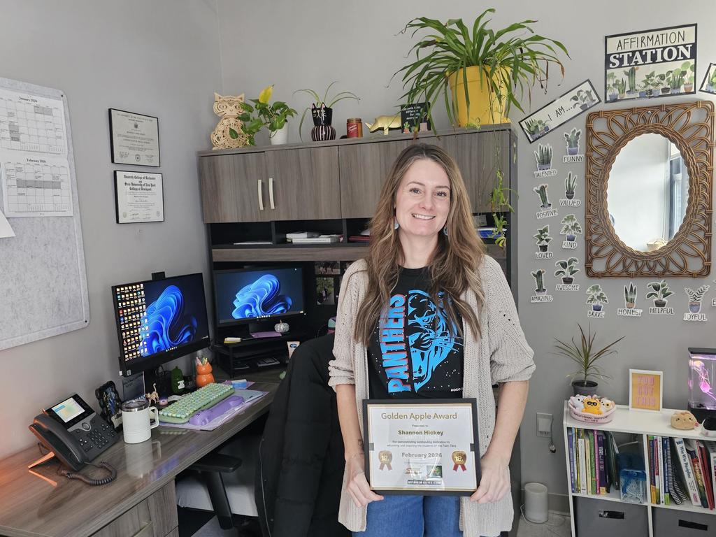 adult standing with certificate in office with panthers shirt on