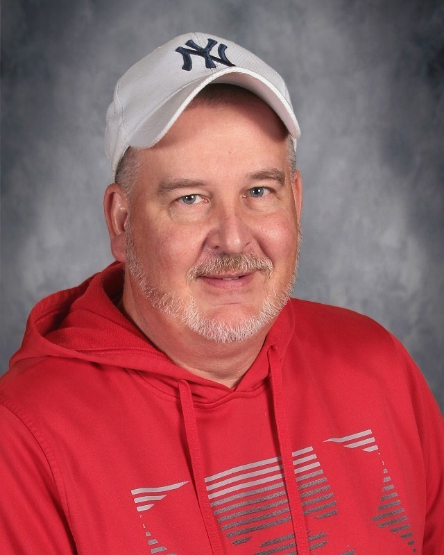 Head shot picture of person wearing a red sweatshirt with a yankees hat