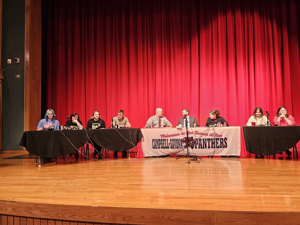 Academic All stars on stage with panther banner on the table and red curtain behind them.