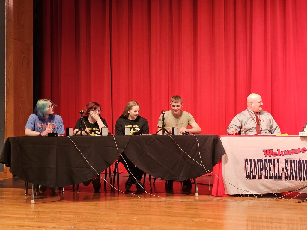Academic All stars on stage with panther banner on the table and red curtain behind them.