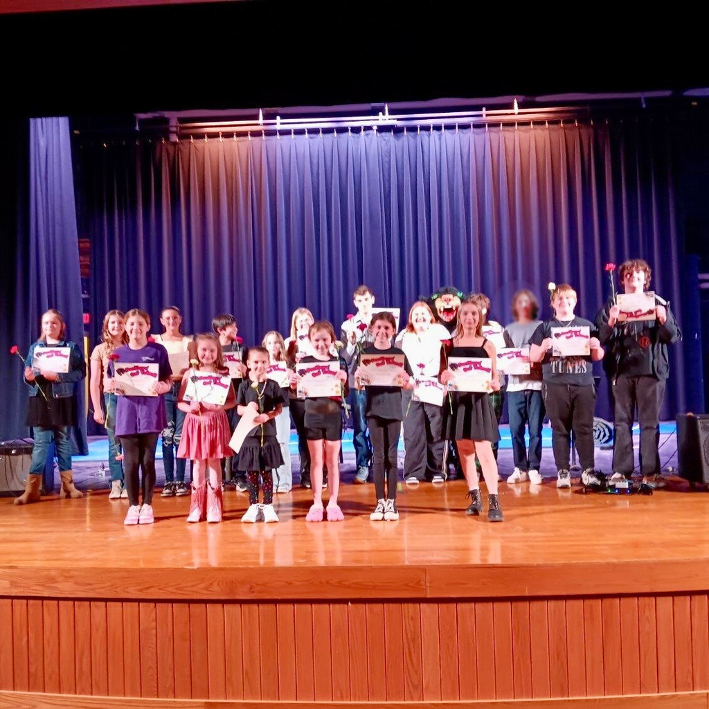 Large group of students standing with certificates on stage at talent show