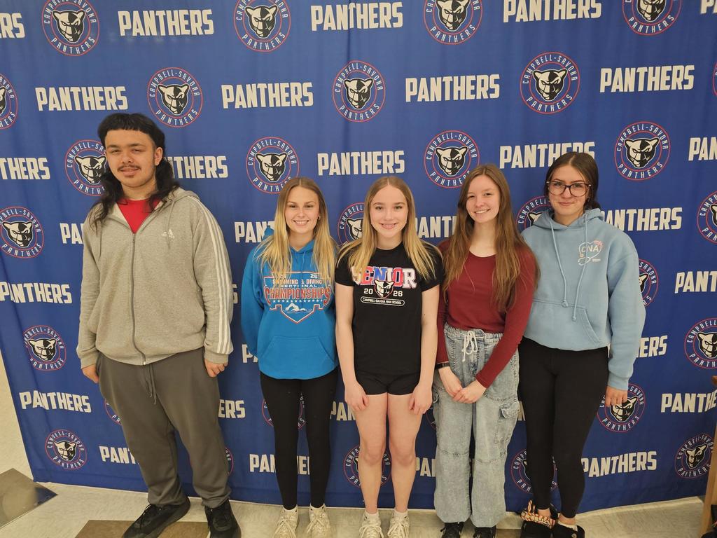 5 students smiling for a picture in front of the panther banner.