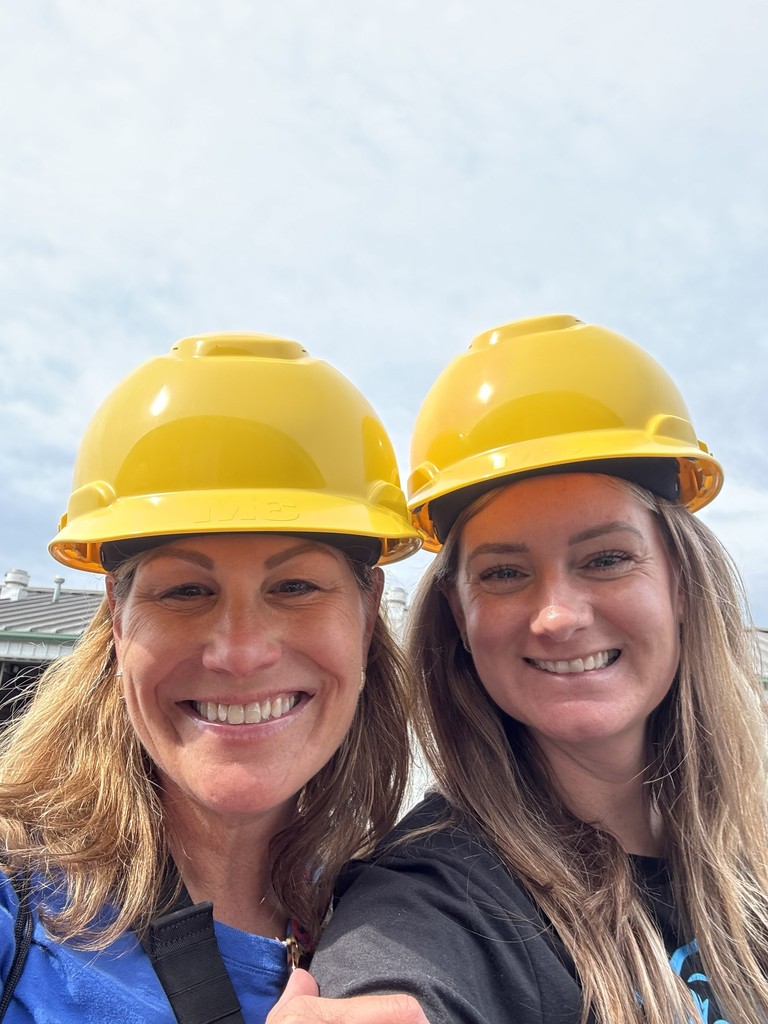 Two adults posing for selfie in hard hats smiling