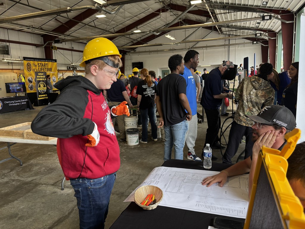 STudent in hard hat and gloves looking at building plans
