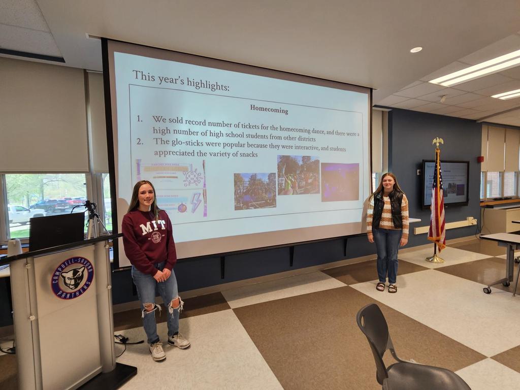 2 student council members standing in front of screen