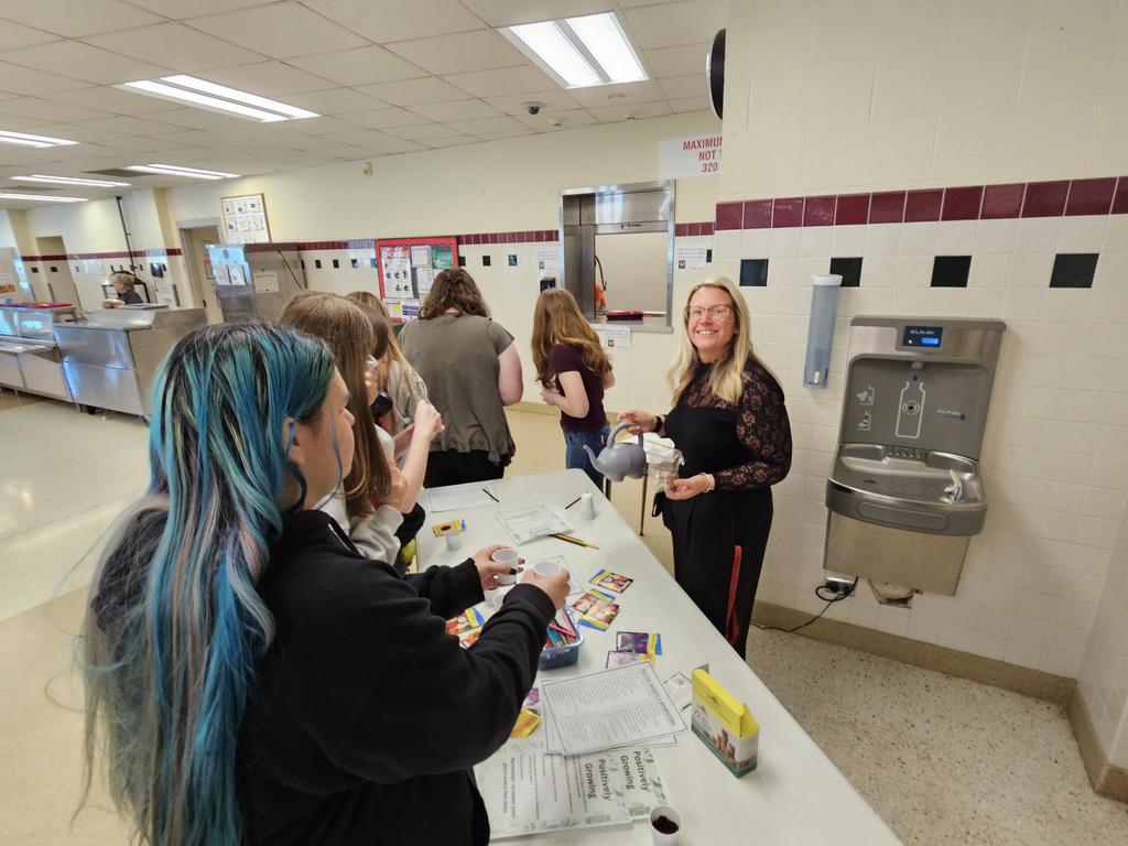 Teacher smiling while helping student plant seeds.