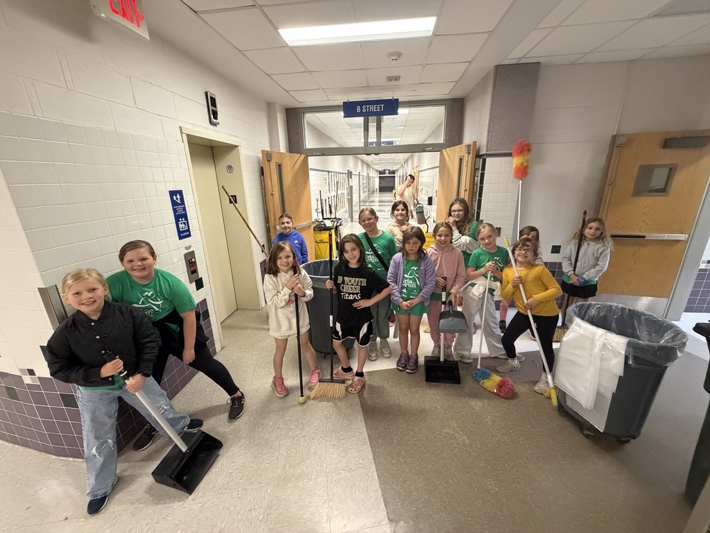 GOTR students posing with brooms and dustpans cleaning the school