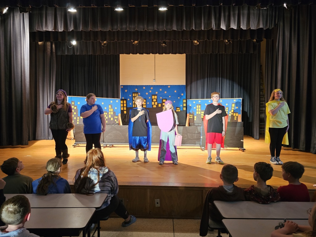 Students on stage hand on hearts
