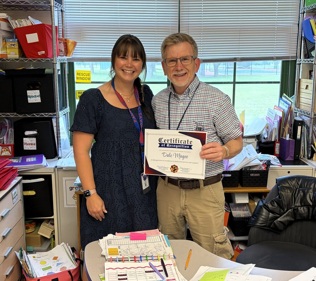 girl in black dress and man in plade shirt smiling holding certificate
