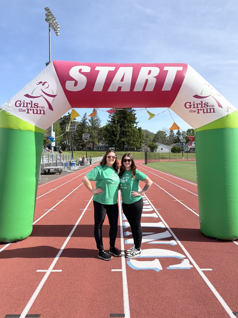 Two girls posing in front of the starting line on the track in green shirts