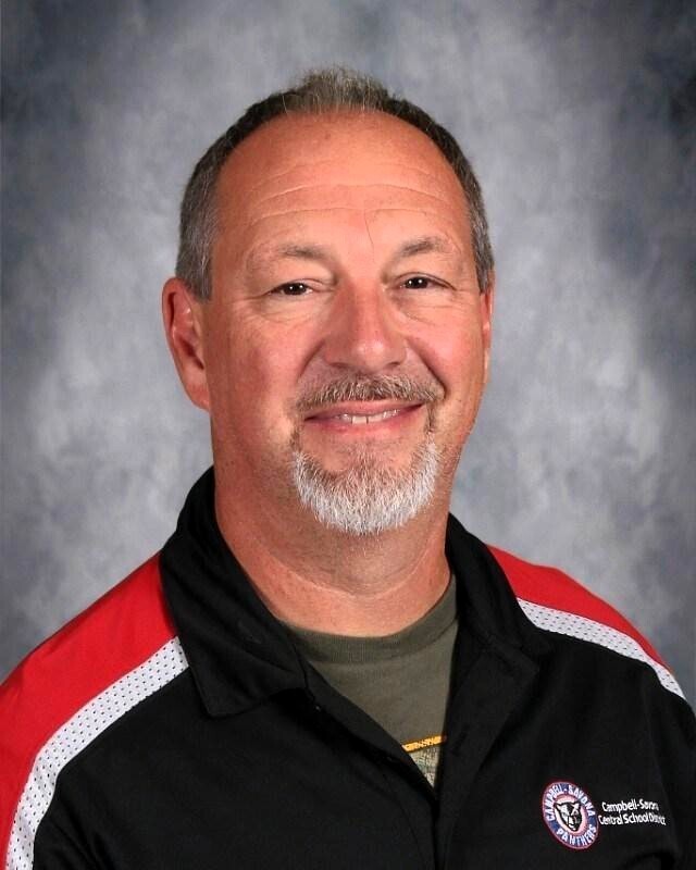 School picture of man with beard and black and red uniform