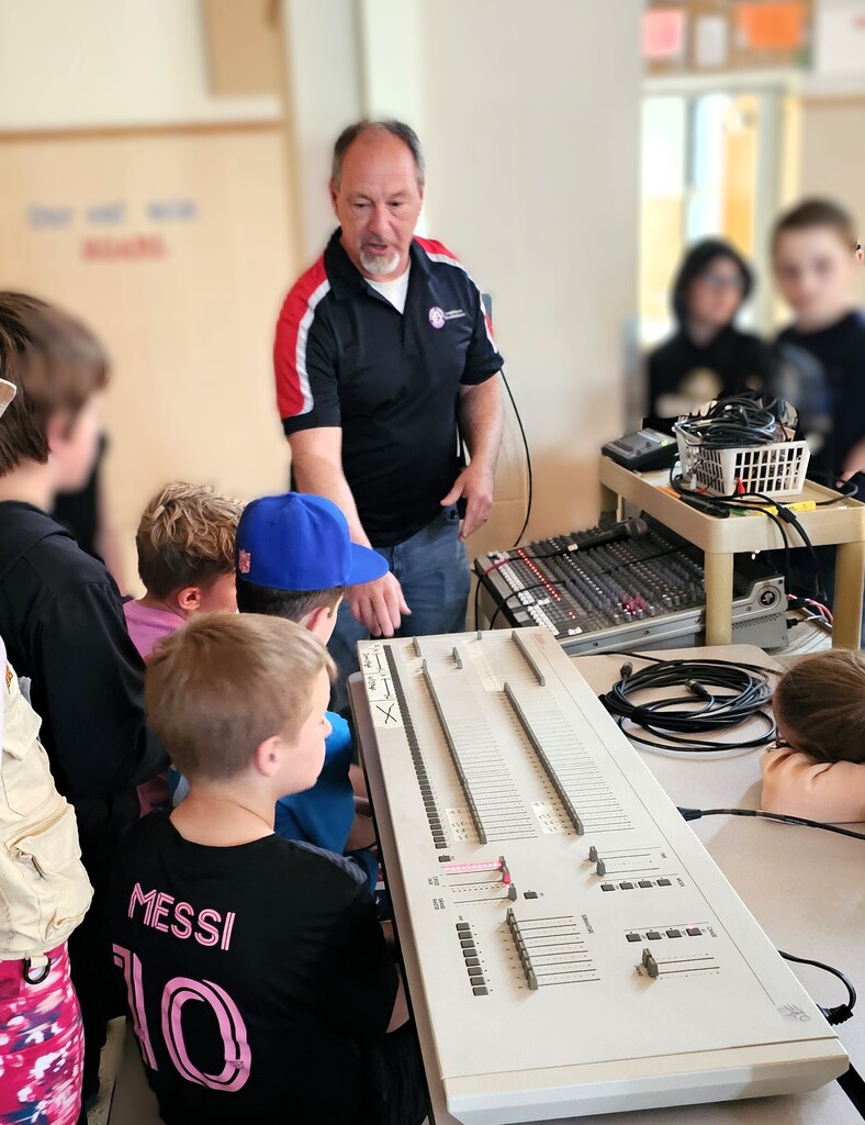 Man at light board teaching students