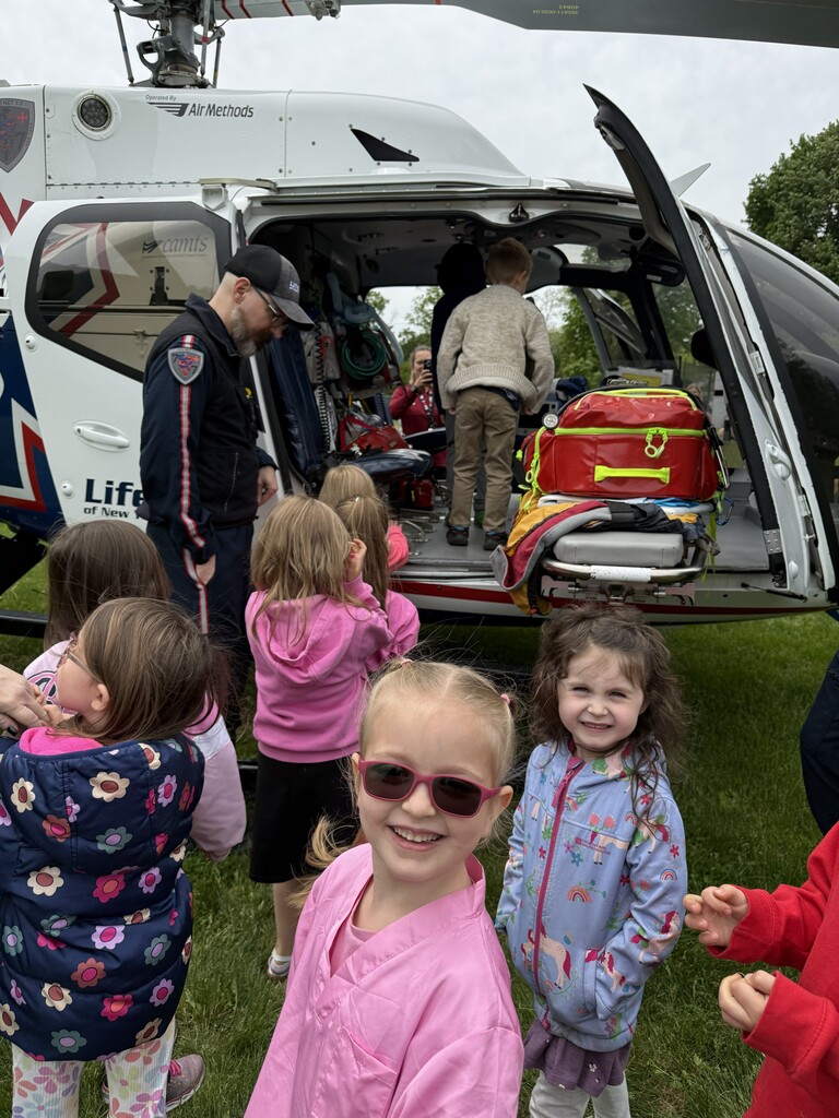 Students standing at helicopter one in sunglasses smiling at camera