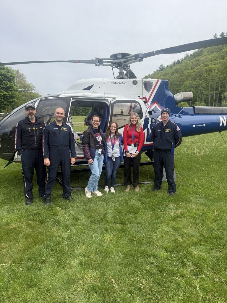 Group photo of adults standing in front of a helicopter