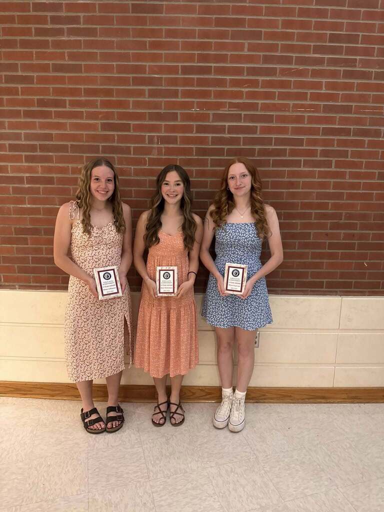 3 studnets in dresses holding awards