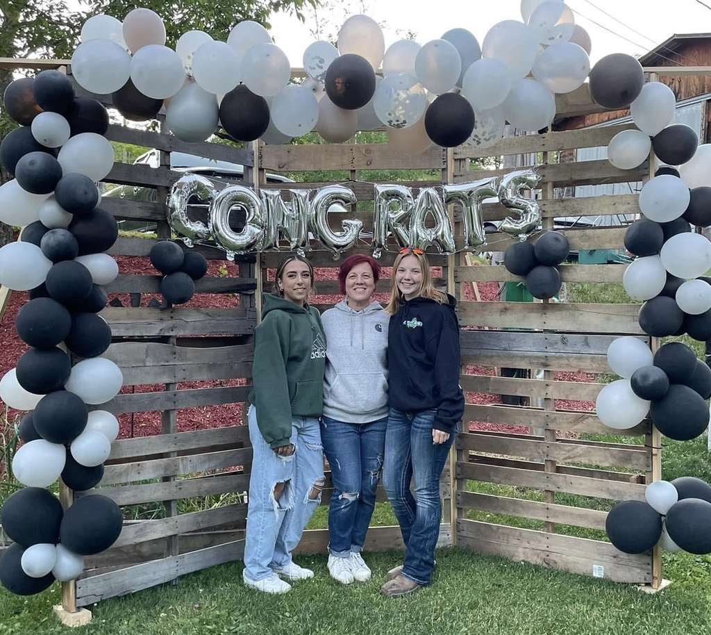Thre girls standing in front of balloon arch with congratulations balloons