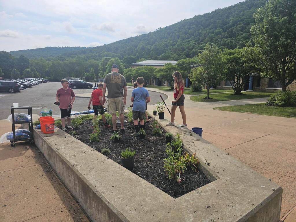 Students and teacher outside planting garden