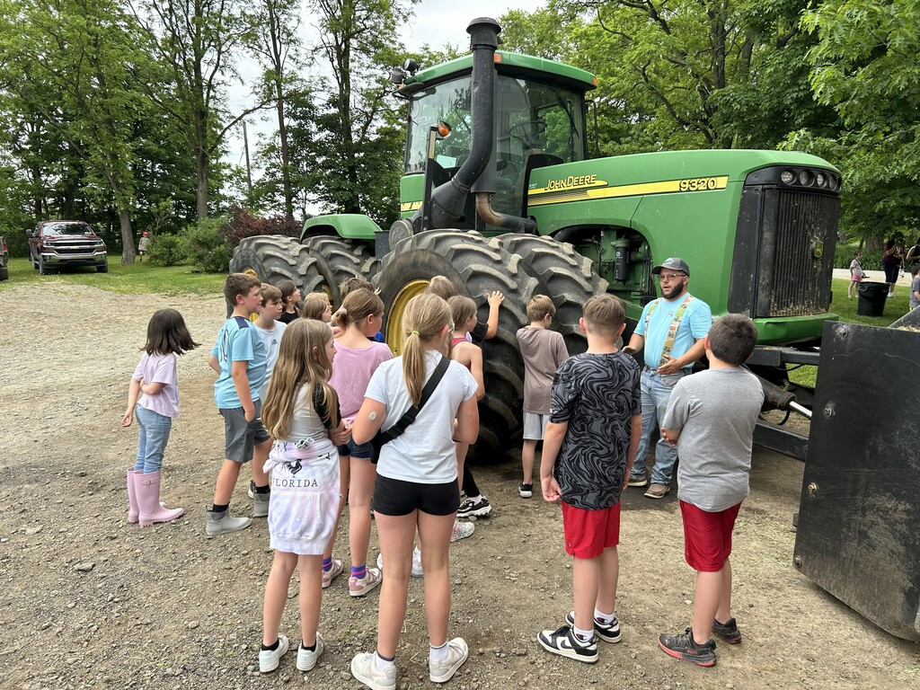 Students looking at a large green tractor