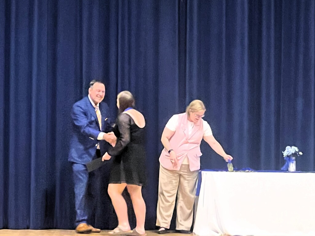 STudent recieving award on stage and shaking hands with presenter