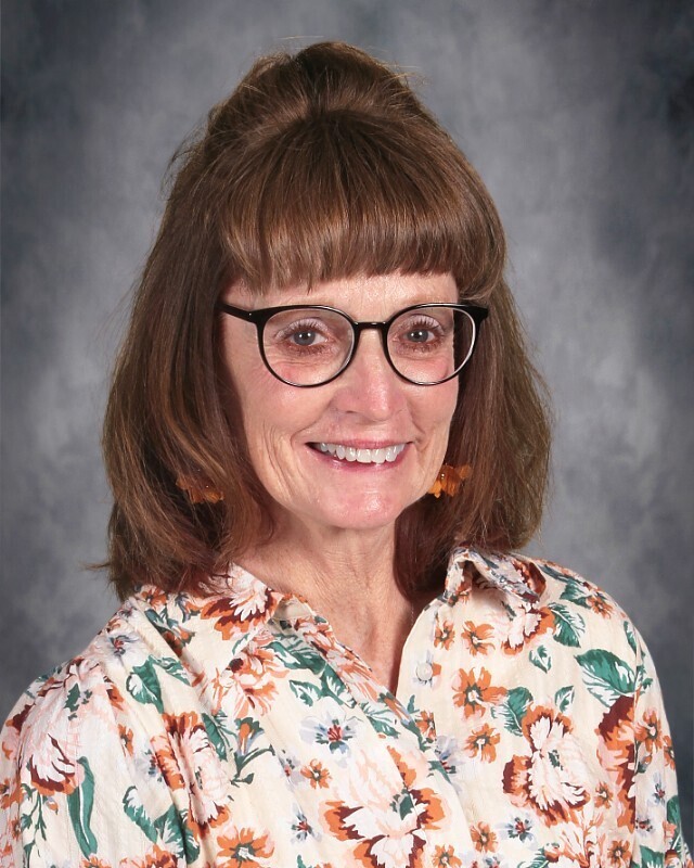 Girl with brown hair glasses and smiling in flower print shirt