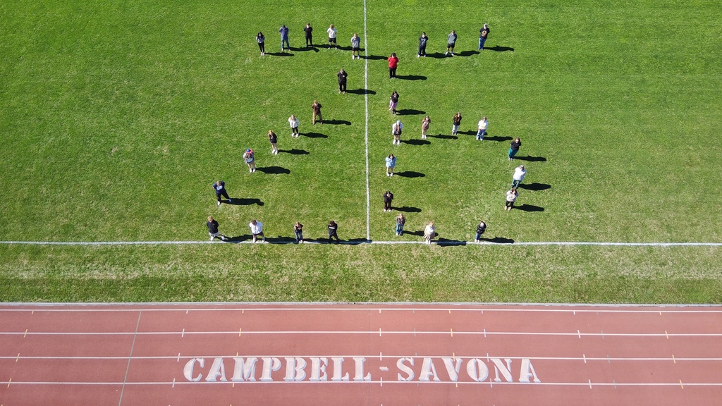 STudents standing in field making a 26