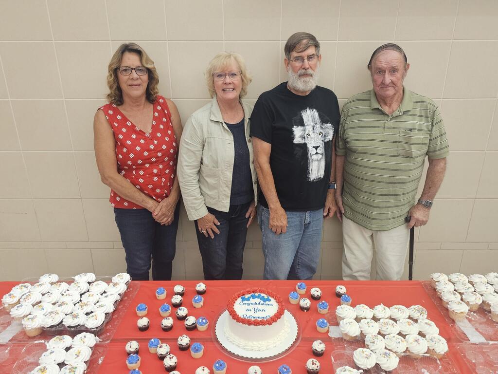 Four people stanidng in front of retirement cake