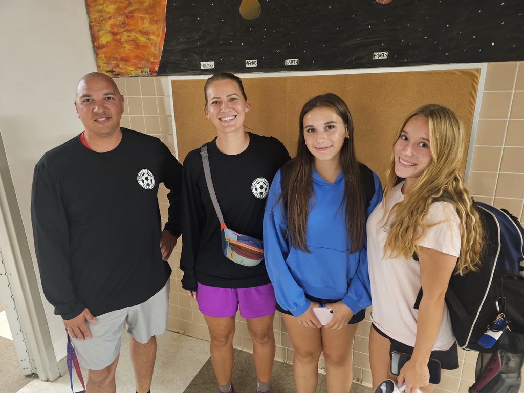 two coaches and two soccer players posing for picture