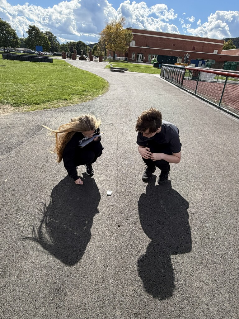 Two students kneeling on sidewalk