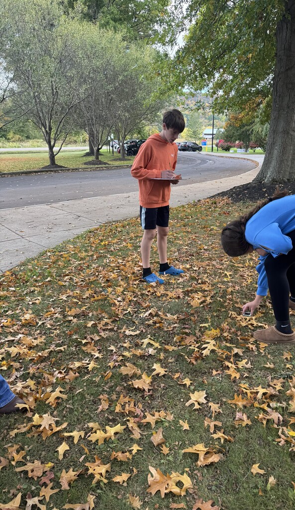 Student in orange shirt with clipboard outside