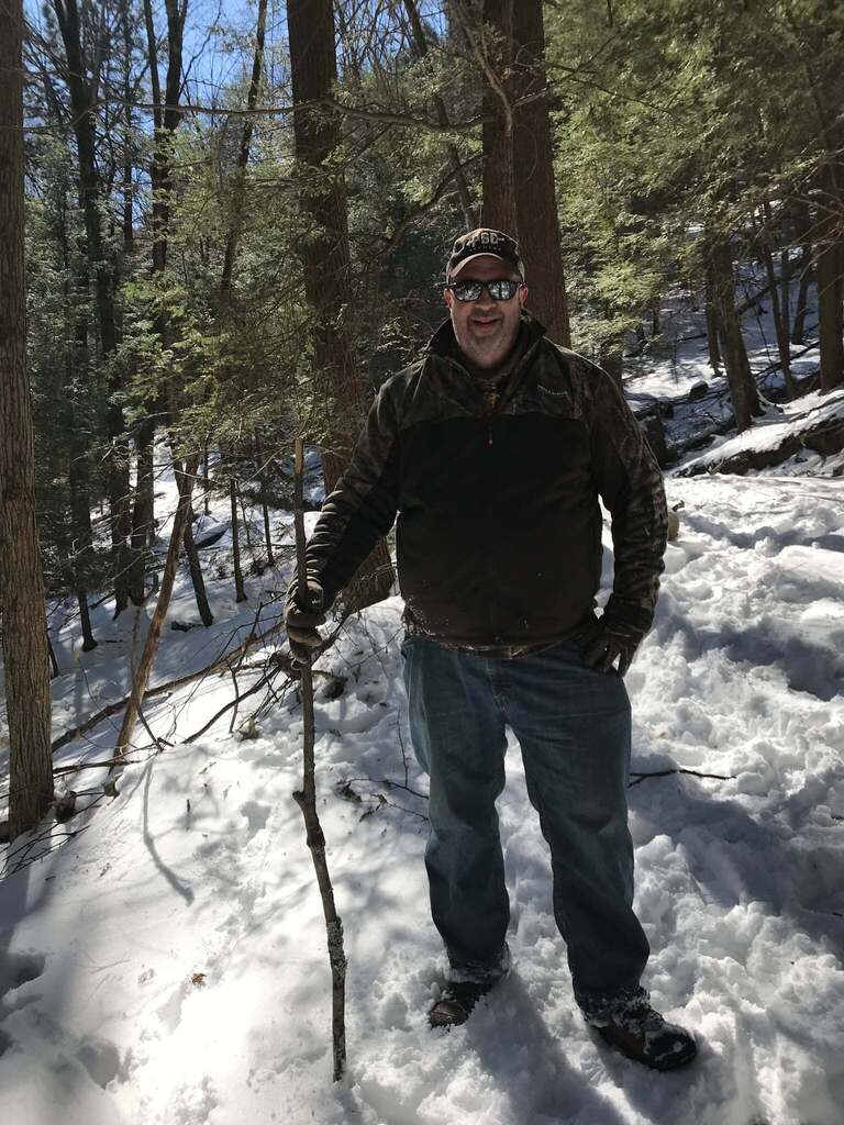 Man walking in the woods with a stick