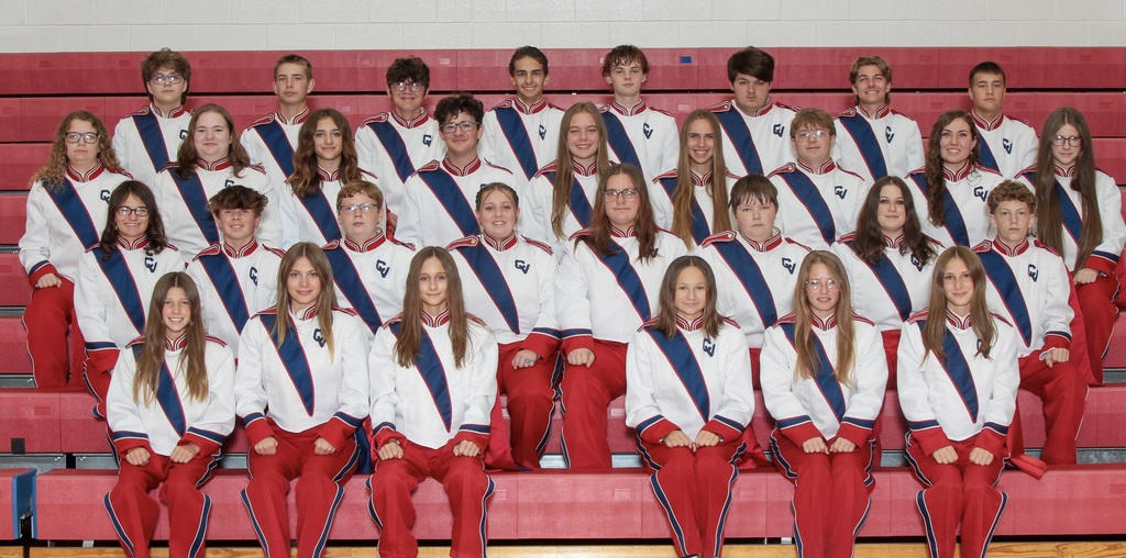 Group photo of Caney Band in their marching uniforms seated in the bleachers. 