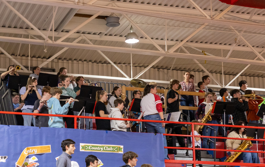 Photo taken looking up into the bleachers as the band plays the national anthem during a basketball game. 