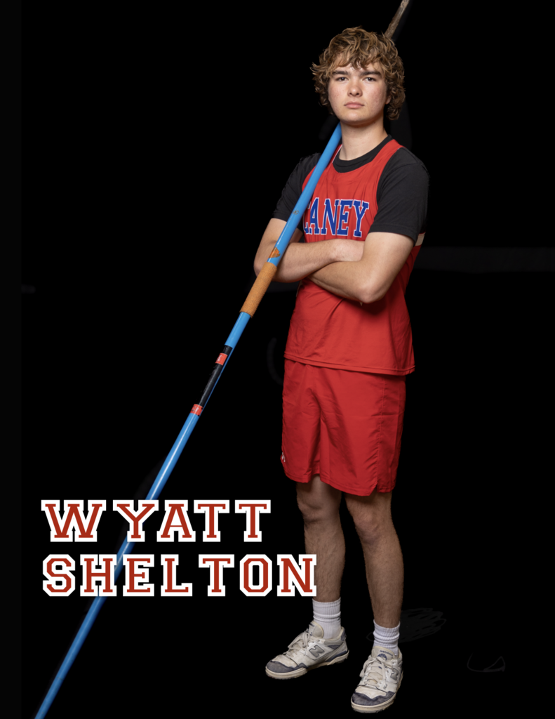 Wyatt Shelton with arms crossed over his chest, javelin leaned against his shoulder