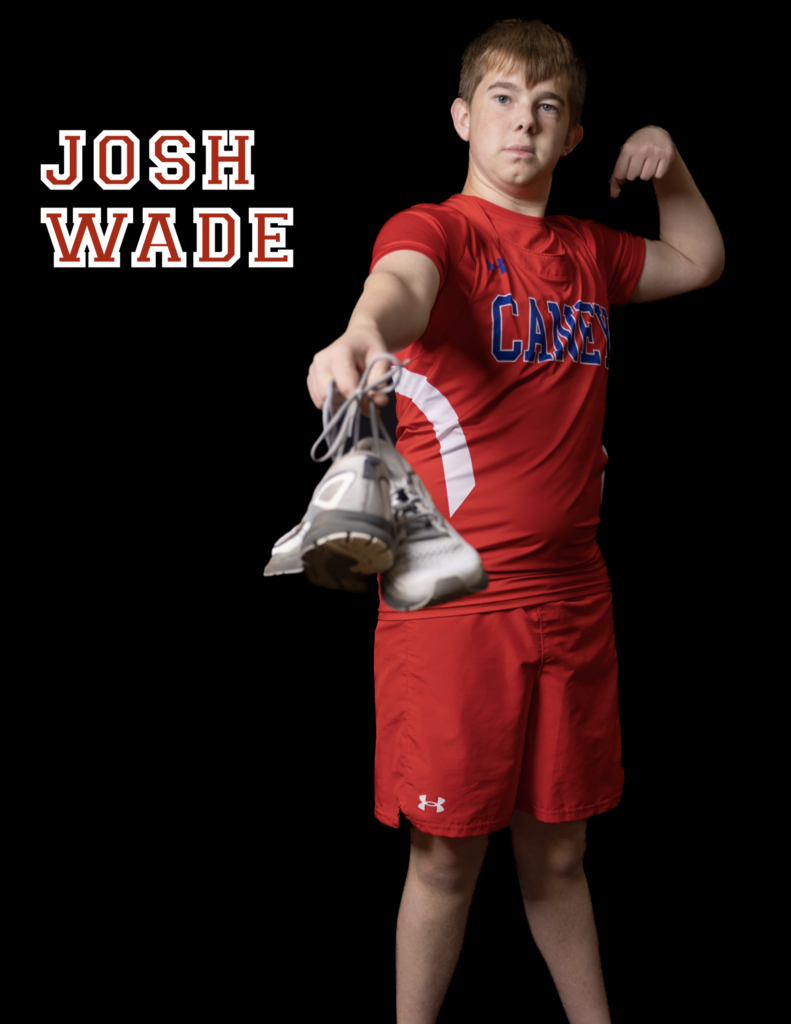 Josh Wade holding shoes out in front of him, other arm flezed in background