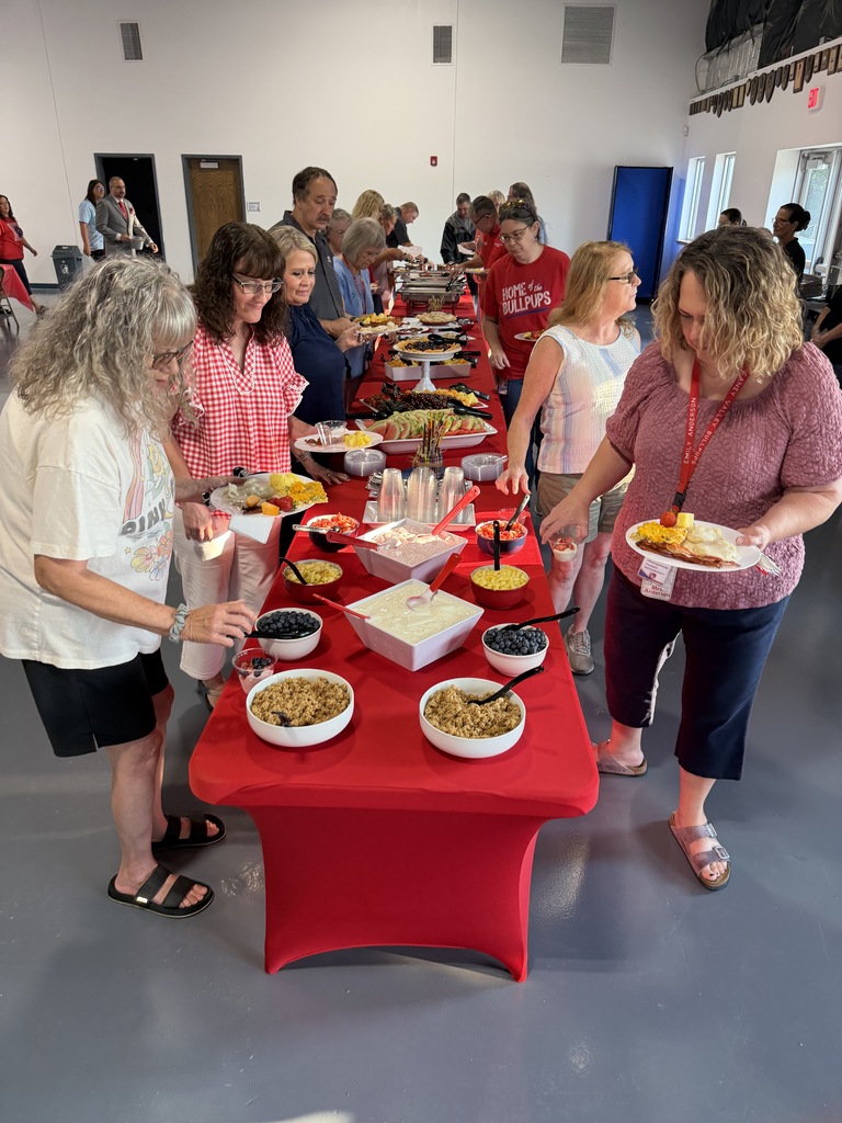 Teachers line up on either side of a beautifully decorated table lined with a breakfast buffet at the welcome back breakfast. 