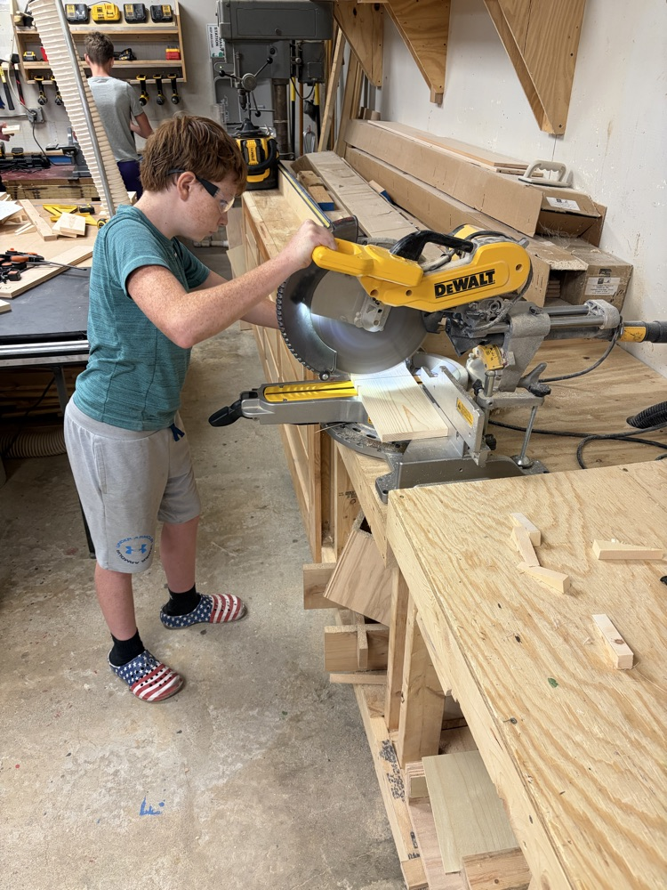 student cutting a board with a saw