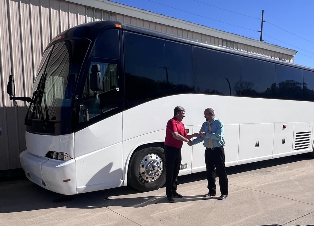 CCC President Marlon Thornburg hands the keys to the charter bus that is being gifted to USD 436 to Superintendent Blake Vargas with the new bus parked in the background. 