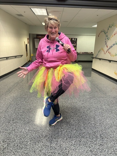 PE teacher in a colorful skirt over her outfit, acting silly and fun