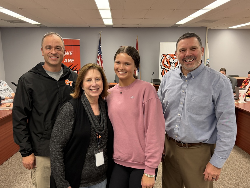 The superintendent, a board member, coach and cheerleader pose for a picture