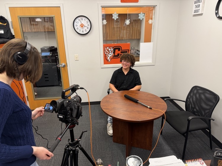 a student speaks into a microphone while sitting in an office