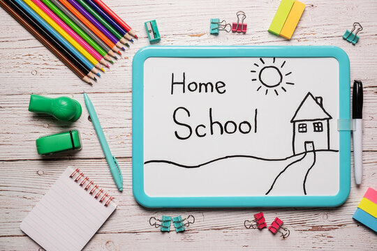 Picture of Home school with pencils and notepads and a white board that has a house and a sun and says Home School