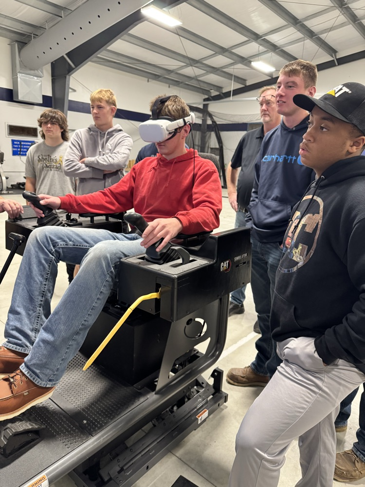 students watching as a classmate uses the CatSimulations machine with VR headset