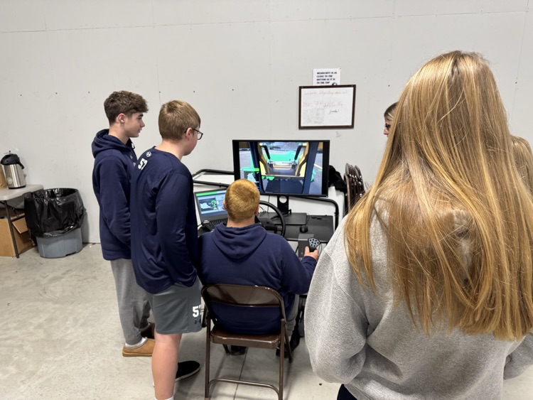 students watching a classmate use the excavator and skid steer sim from CM Labs