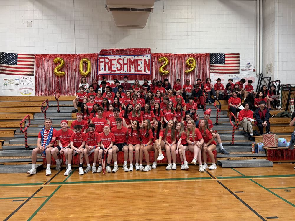 Students sitting on bleachers dressed in red, with 2029 balloons behind them.
