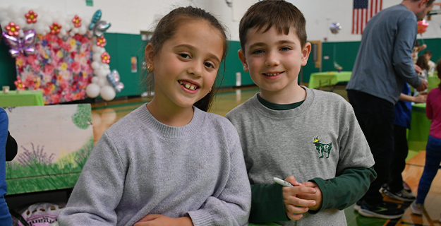 Students smiling together at table.