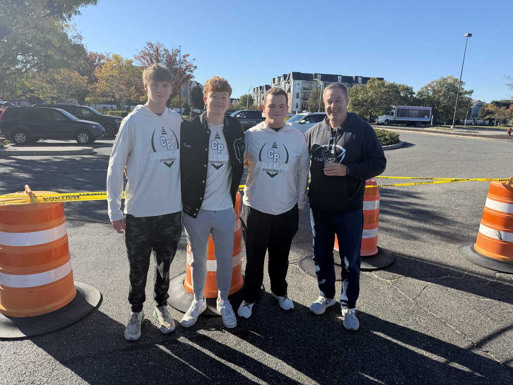Students smiling outside with man.