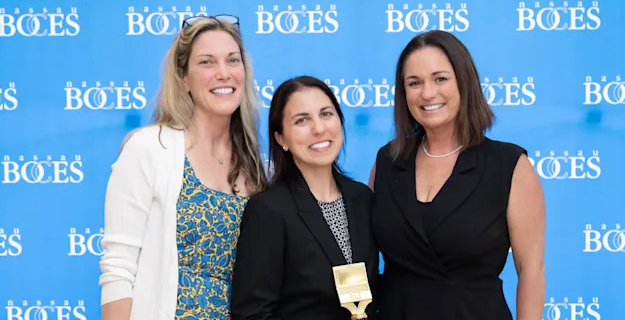 Teachers smiling in front of BOCES wallpaper.